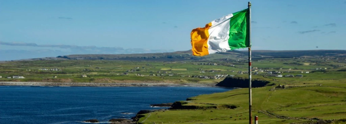 the irish flag flying on a veritcal flagpole